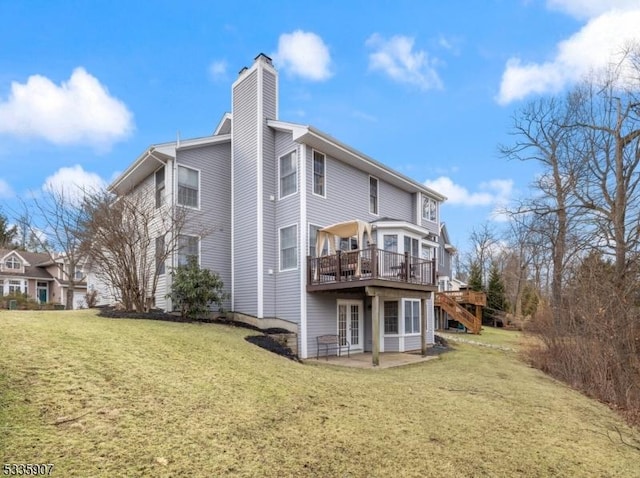 back of house featuring a patio, a chimney, a lawn, and a wooden deck