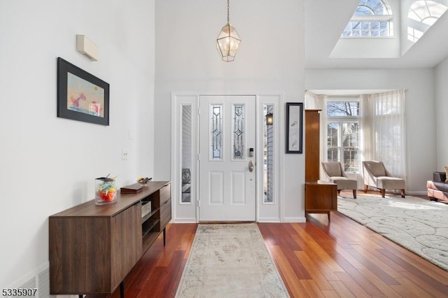 entrance foyer featuring dark wood-style flooring, a high ceiling, baseboards, and an inviting chandelier