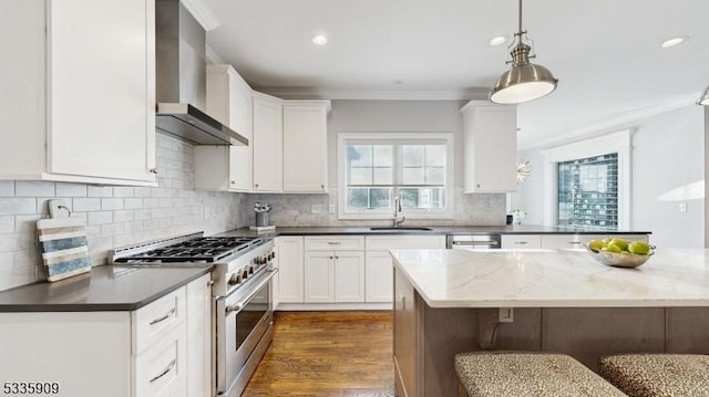 kitchen with wall chimney range hood, sink, white cabinetry, dark stone countertops, and high end stainless steel range