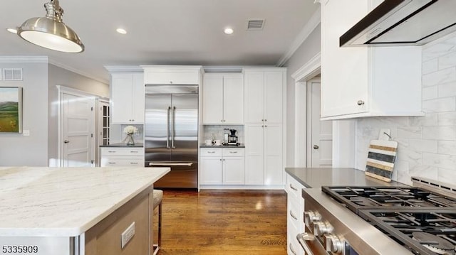 kitchen with crown molding, white cabinetry, dark stone countertops, stainless steel appliances, and range hood