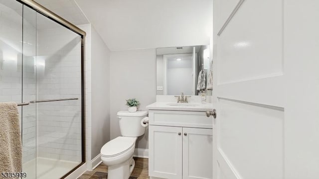 bathroom featuring vanity, toilet, a shower with shower door, and wood-type flooring