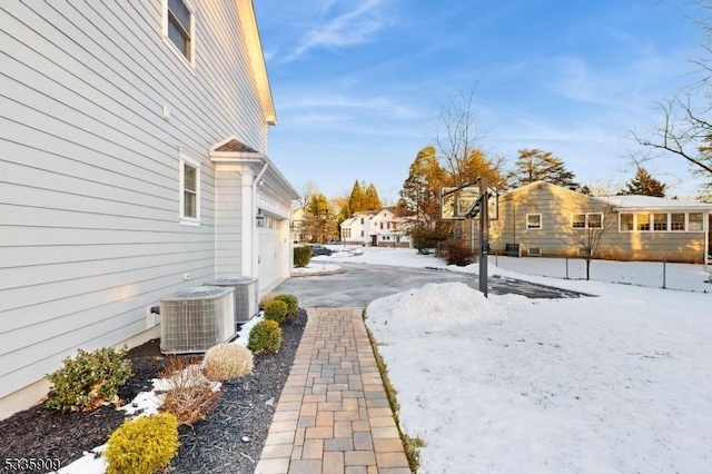 snowy yard with cooling unit and a garage