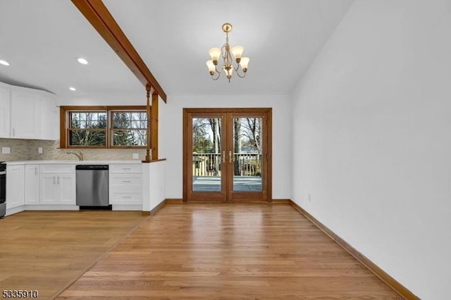 kitchen with french doors, stainless steel dishwasher, pendant lighting, light hardwood / wood-style floors, and white cabinets