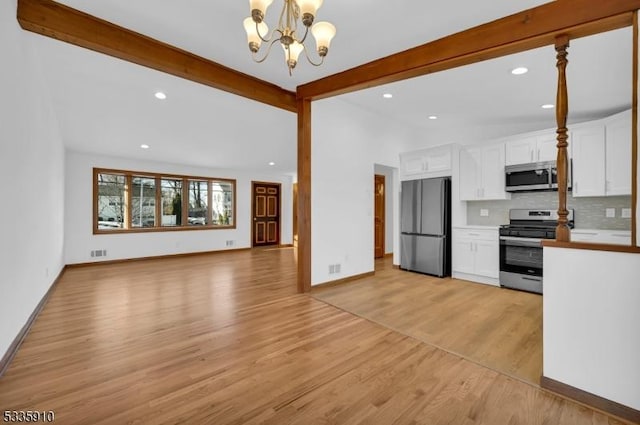 kitchen with decorative light fixtures, tasteful backsplash, white cabinets, stainless steel appliances, and light wood-type flooring