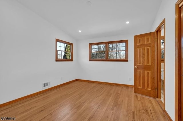 unfurnished room featuring lofted ceiling and light hardwood / wood-style floors