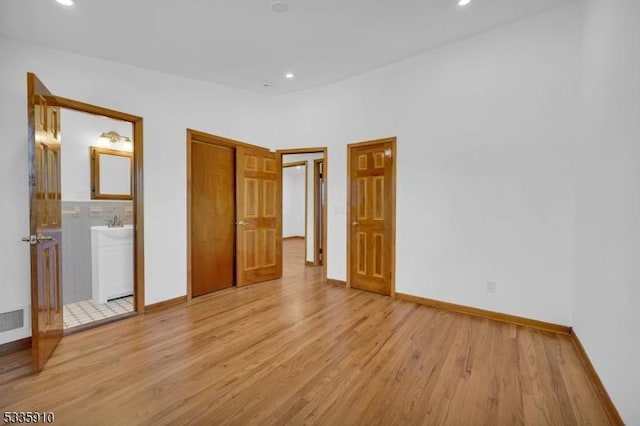 unfurnished bedroom with connected bathroom and light wood-type flooring