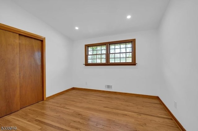 unfurnished bedroom featuring lofted ceiling, light wood-type flooring, and a closet