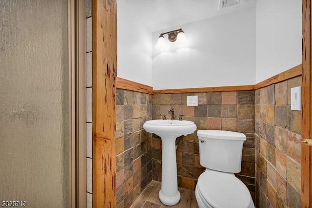 bathroom featuring tile walls and toilet