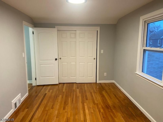 unfurnished bedroom featuring dark hardwood / wood-style floors and a closet