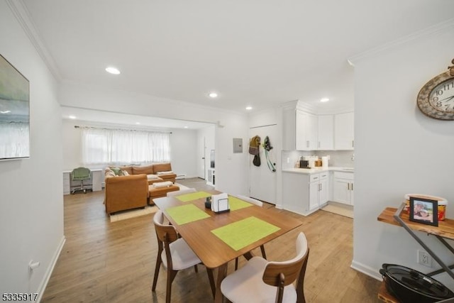 dining room with light wood finished floors, baseboards, ornamental molding, and recessed lighting