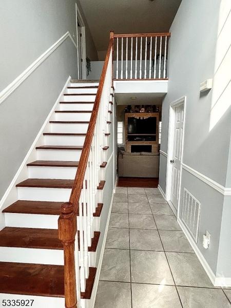 stairway featuring tile patterned flooring, visible vents, and baseboards