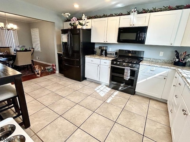 kitchen featuring light stone counters, light tile patterned flooring, white cabinetry, black appliances, and an inviting chandelier