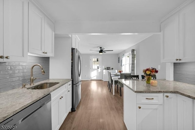 kitchen featuring light stone counters, appliances with stainless steel finishes, kitchen peninsula, and white cabinets