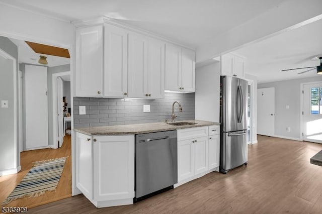 kitchen with appliances with stainless steel finishes, light stone countertops, sink, and white cabinets