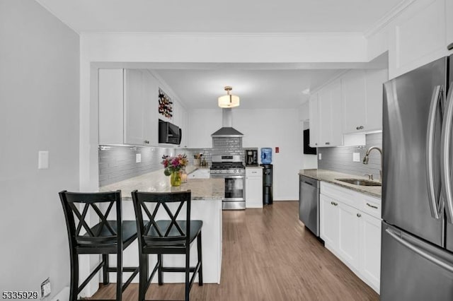 kitchen featuring sink, a breakfast bar, appliances with stainless steel finishes, white cabinets, and kitchen peninsula