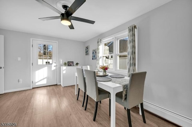 dining area with ceiling fan, baseboard heating, and light hardwood / wood-style flooring