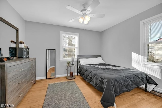 bedroom with multiple windows, ceiling fan, and light wood-type flooring