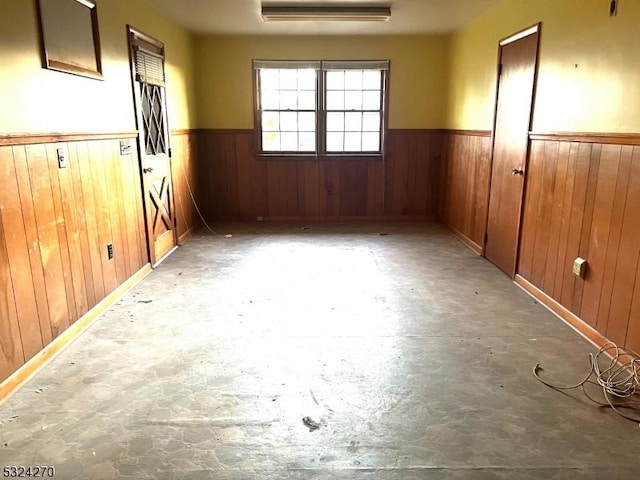 spare room featuring a wall mounted air conditioner, concrete flooring, and wood walls