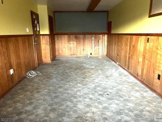 empty room with wooden walls and beam ceiling