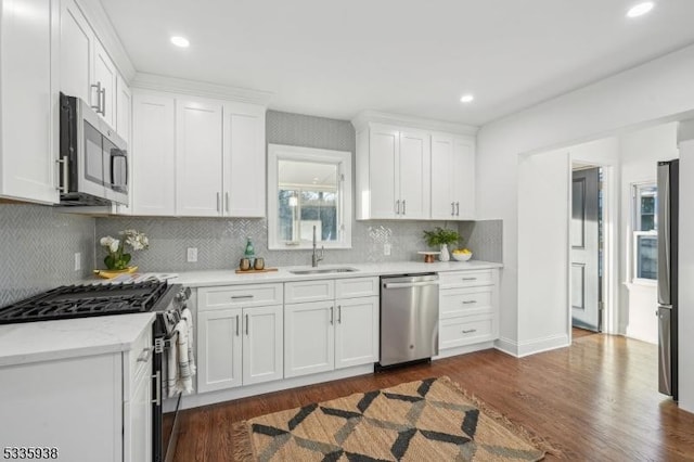 kitchen with stainless steel appliances, sink, white cabinets, and dark hardwood / wood-style floors