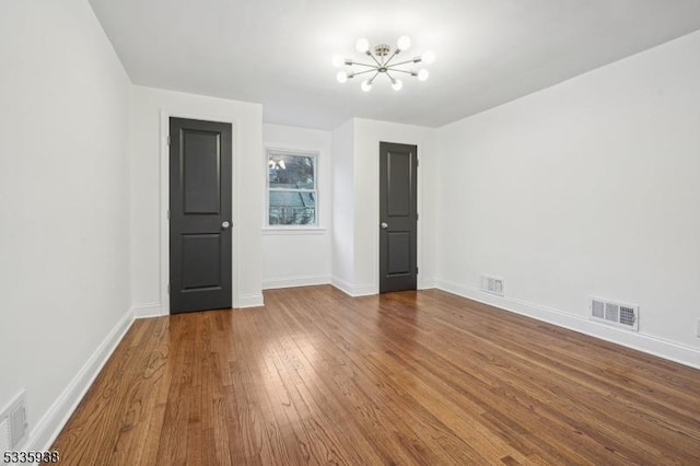 empty room featuring hardwood / wood-style floors and a notable chandelier