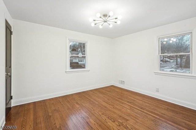 spare room with hardwood / wood-style flooring and a chandelier