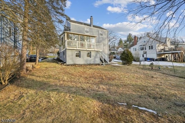 rear view of property with a balcony and a lawn