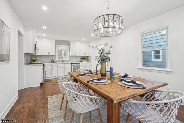 dining room featuring a healthy amount of sunlight, dark wood-type flooring, and a notable chandelier