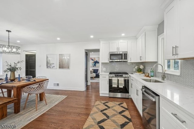 kitchen with stainless steel appliances, sink, white cabinets, and decorative light fixtures