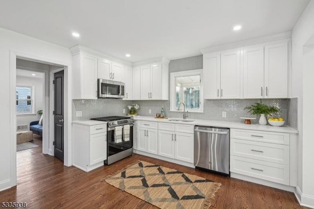 kitchen with appliances with stainless steel finishes, sink, dark wood-type flooring, and white cabinets