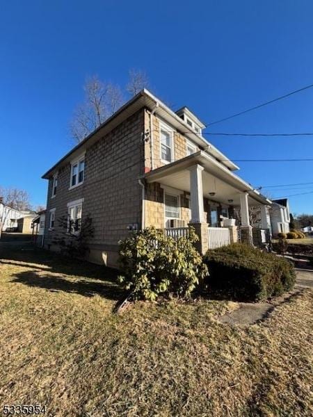 view of property exterior with a porch and a lawn