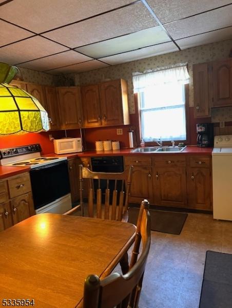 kitchen featuring washer / dryer, sink, a drop ceiling, and white appliances