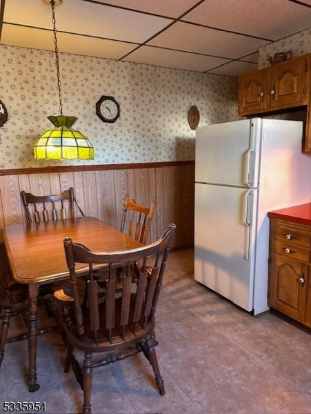 dining space with a paneled ceiling and wood walls