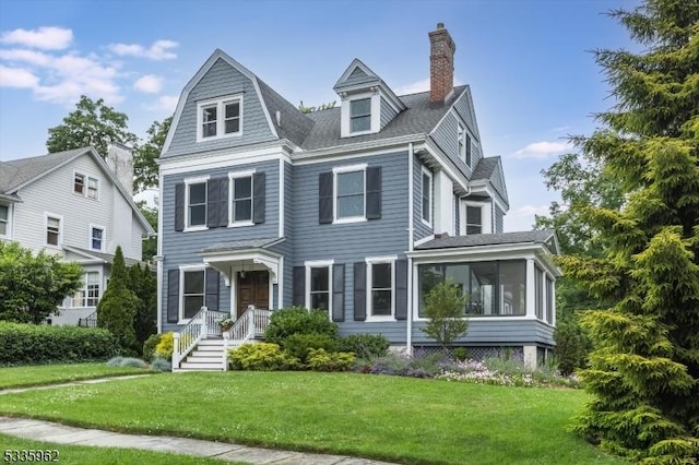 view of front of house featuring a sunroom and a front lawn