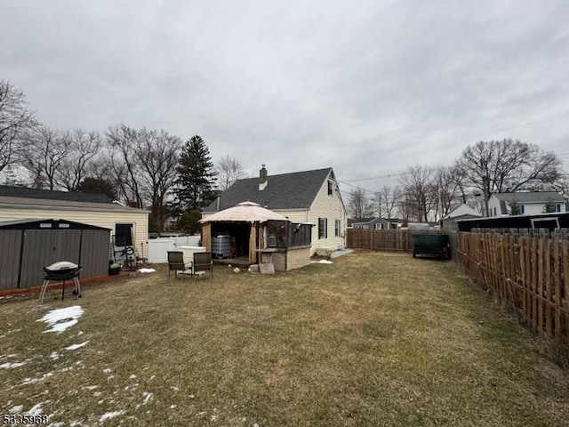 back of property featuring a gazebo, a storage shed, and a lawn