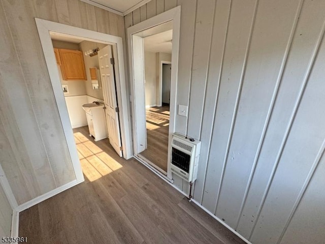 hall featuring crown molding, wooden walls, dark wood finished floors, and heating unit