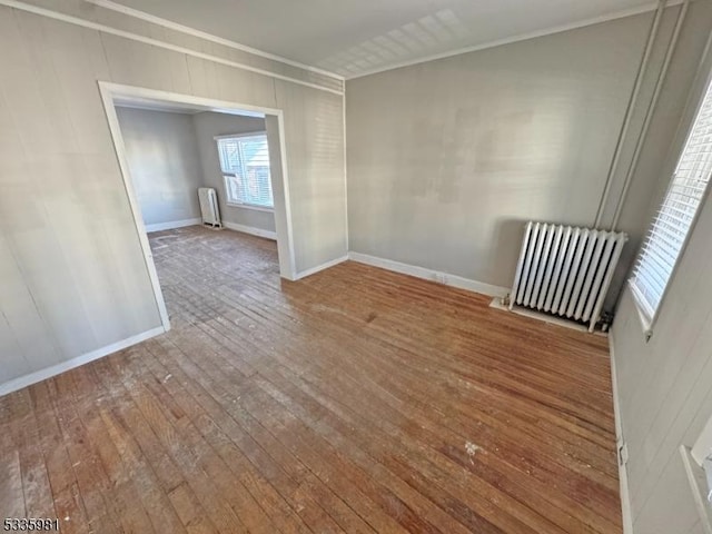 empty room with ornamental molding, hardwood / wood-style flooring, and radiator