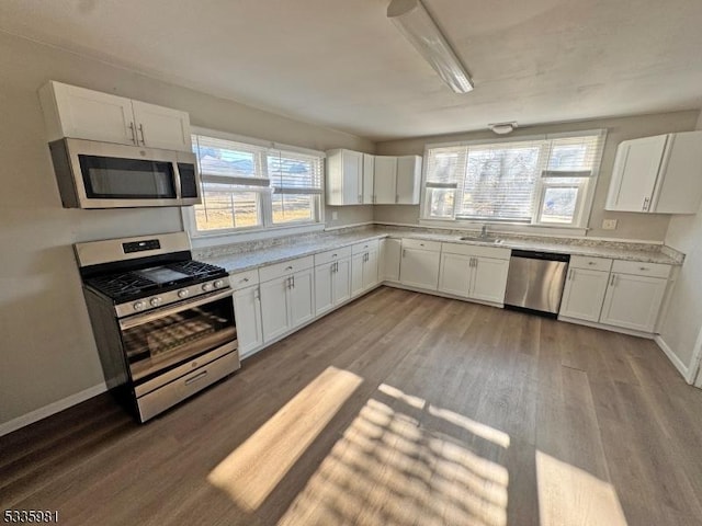 kitchen featuring appliances with stainless steel finishes, light countertops, light wood-style flooring, and white cabinetry