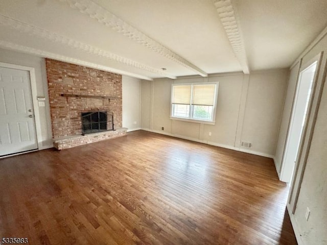 unfurnished living room with beamed ceiling, dark hardwood / wood-style floors, and a brick fireplace