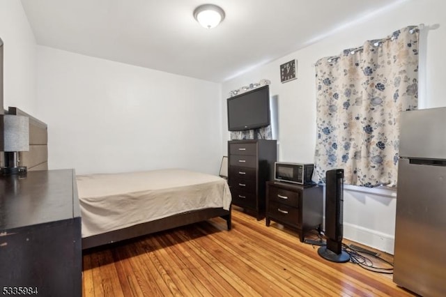 bedroom with light wood finished floors and freestanding refrigerator