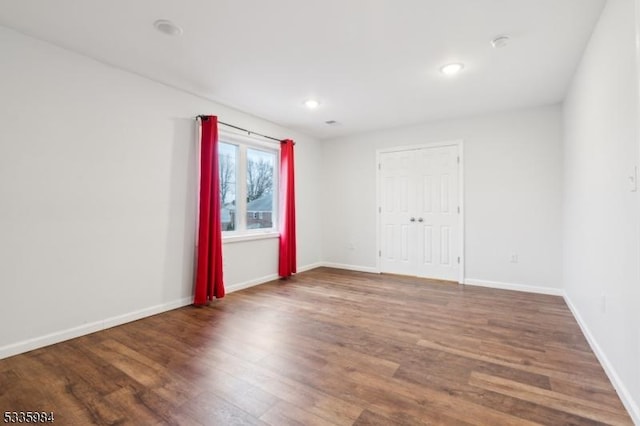 empty room with recessed lighting, wood finished floors, and baseboards