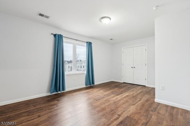 unfurnished room featuring wood finished floors, visible vents, and baseboards