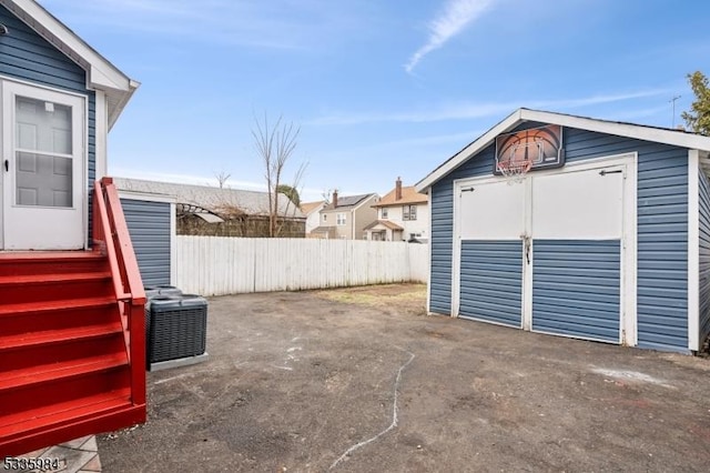 exterior space with central AC unit, a storage shed, fence, and an outbuilding