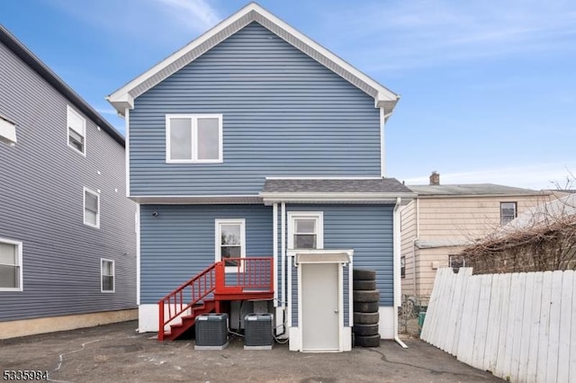 rear view of house with cooling unit and fence