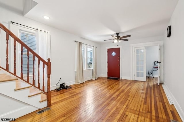 foyer entrance with baseboards, stairway, visible vents, and hardwood / wood-style flooring