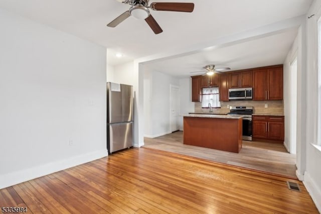 kitchen featuring stainless steel appliances, visible vents, baseboards, light wood-style floors, and a center island