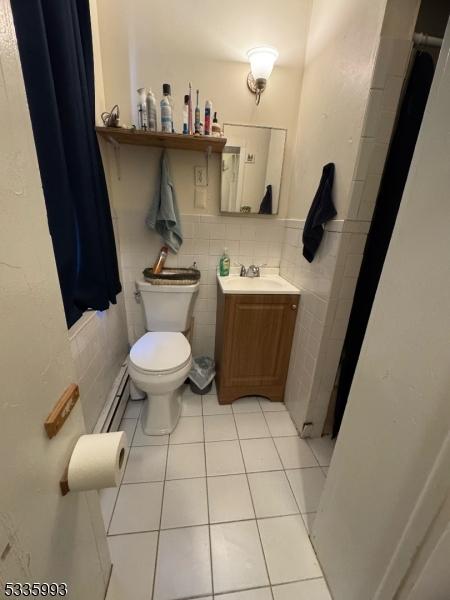 bathroom with vanity, tile walls, tile patterned floors, and toilet