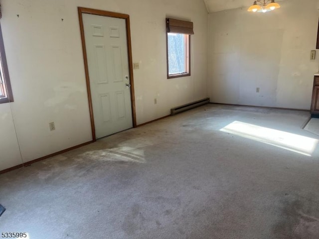 spare room featuring light colored carpet, a chandelier, vaulted ceiling, and a baseboard heating unit