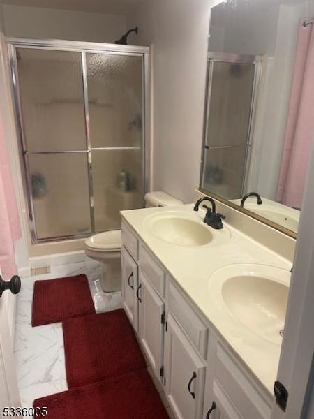 bathroom featuring vanity, toilet, and an enclosed shower