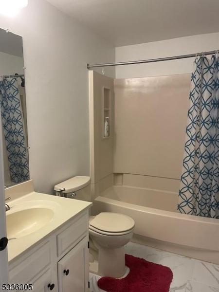 full bathroom with shower / tub combo with curtain, vanity, and toilet